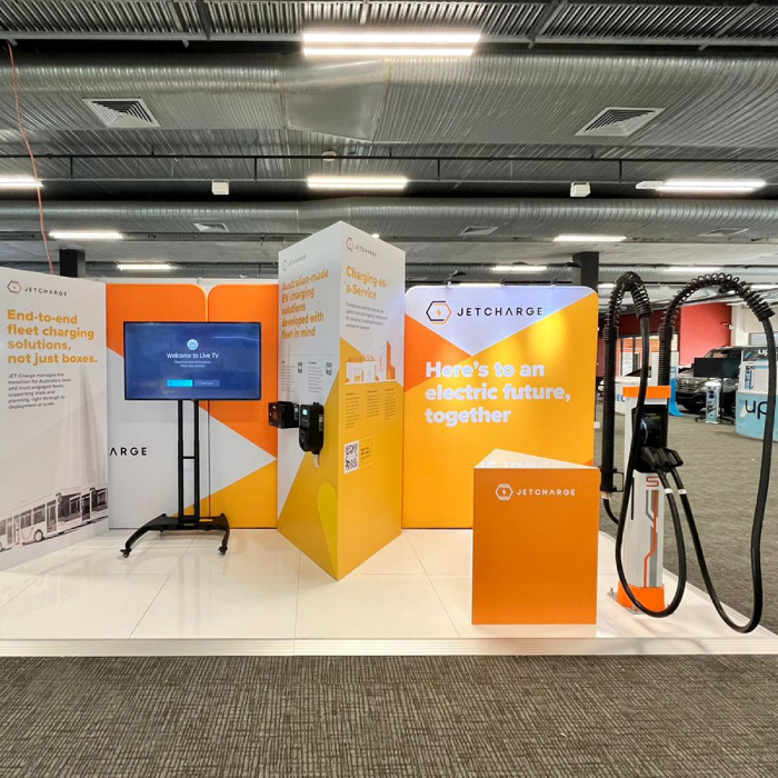JetCharge exhibition stand with orange and white panels, a screen and EV chargers