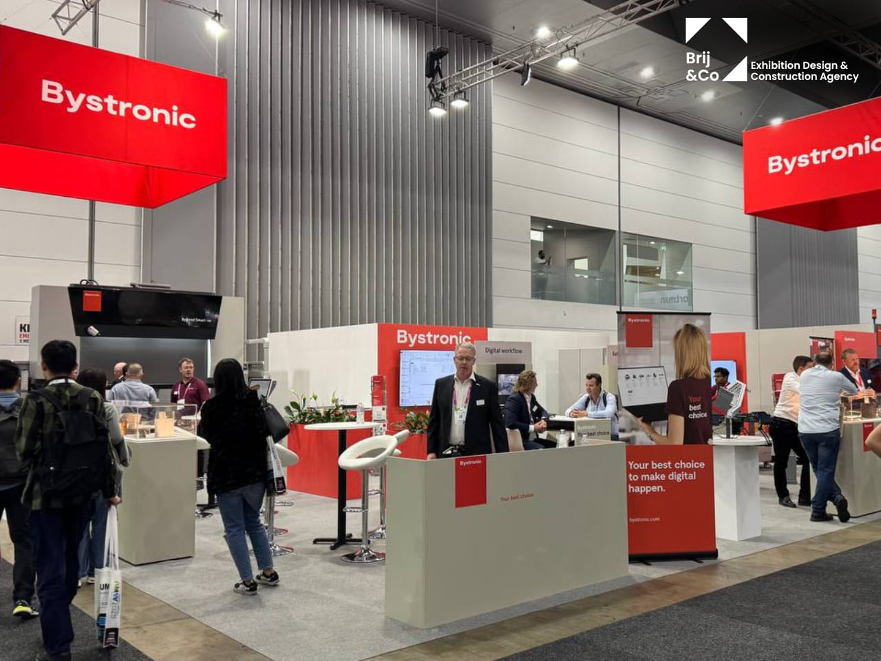 Bystronic exhibition stand with red hanging banners and meeting tables