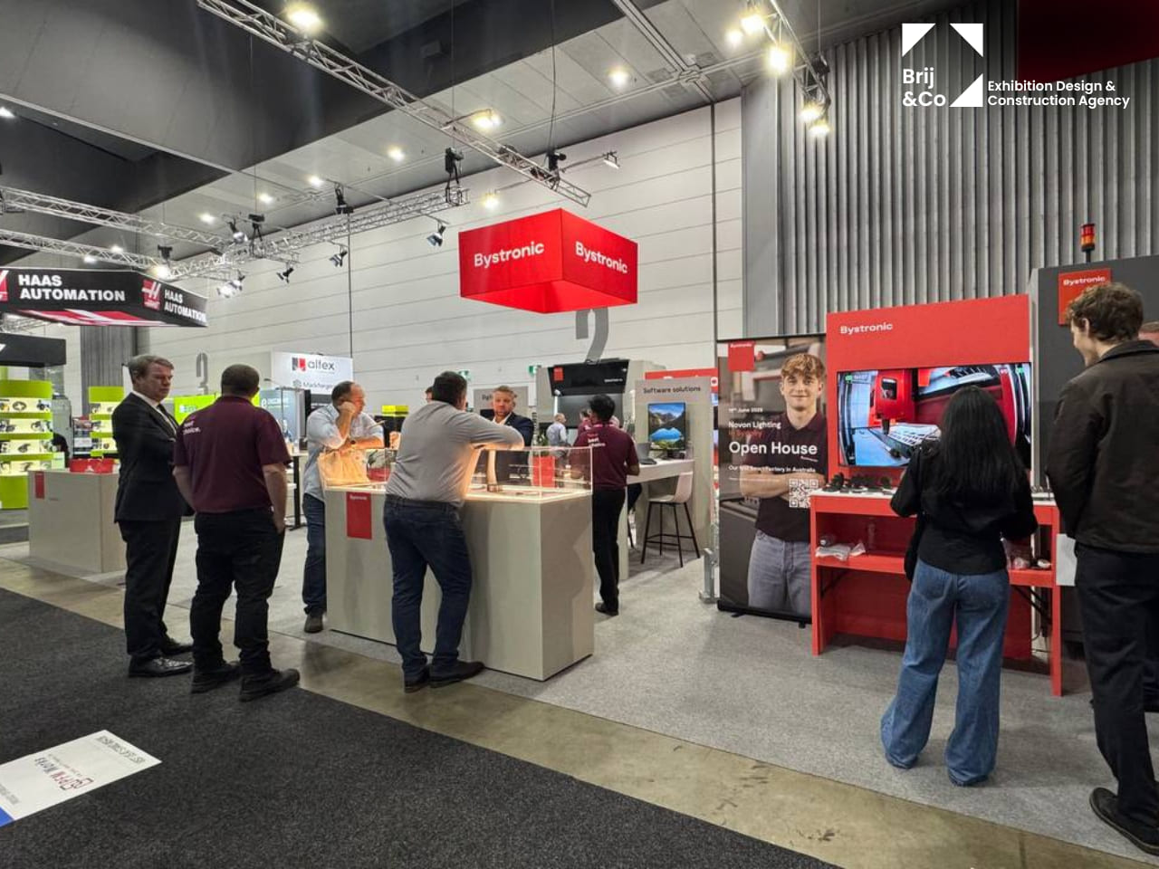 Bystronic exhibition stand with red hanging banners and visitors