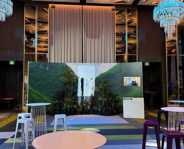 Networking event set with a waterfall backdrop and high tables