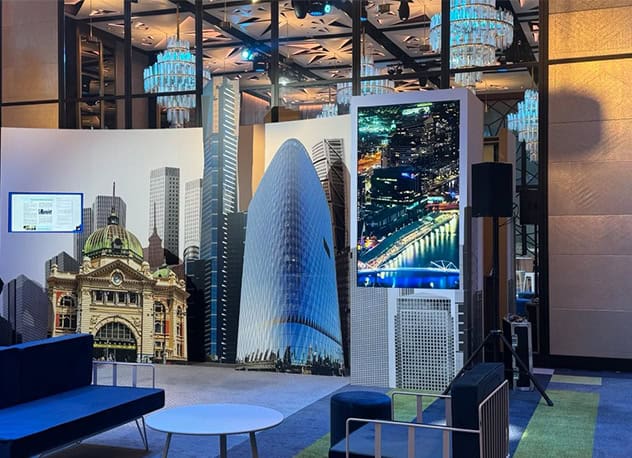 Networking event backdrop with a printed Melbourne skyline and a digital screen