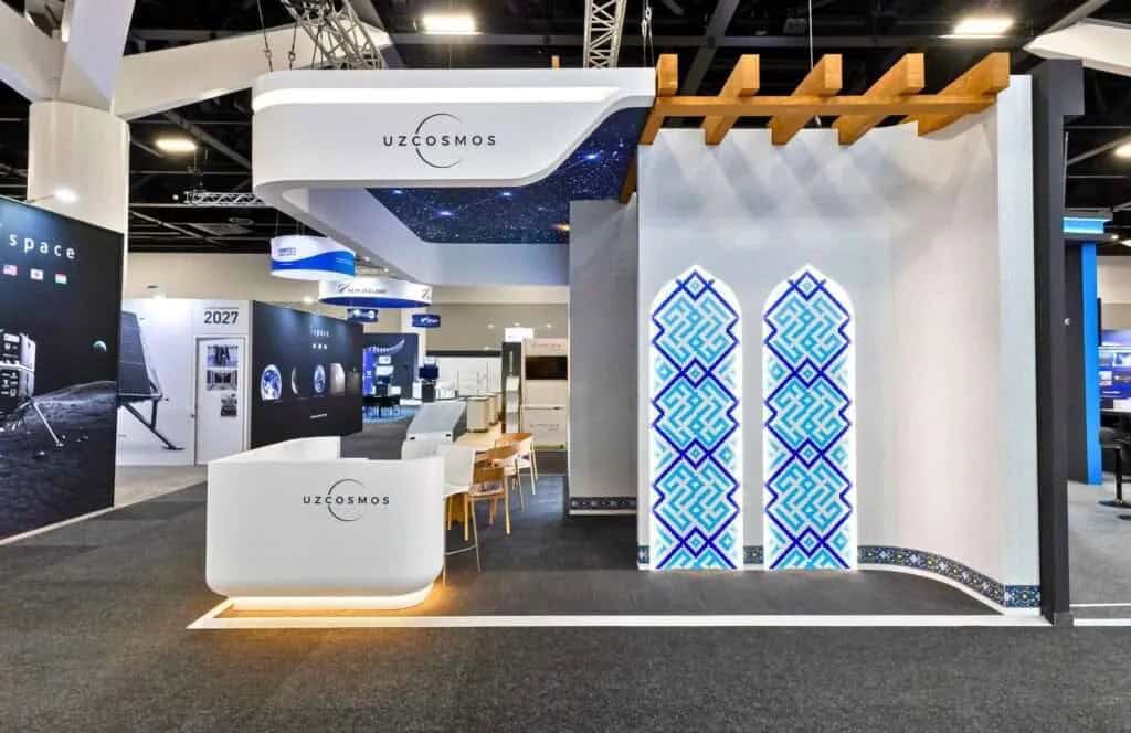 Uzcosmos exhibition stand with white walls, a patterned column and a timber pergola