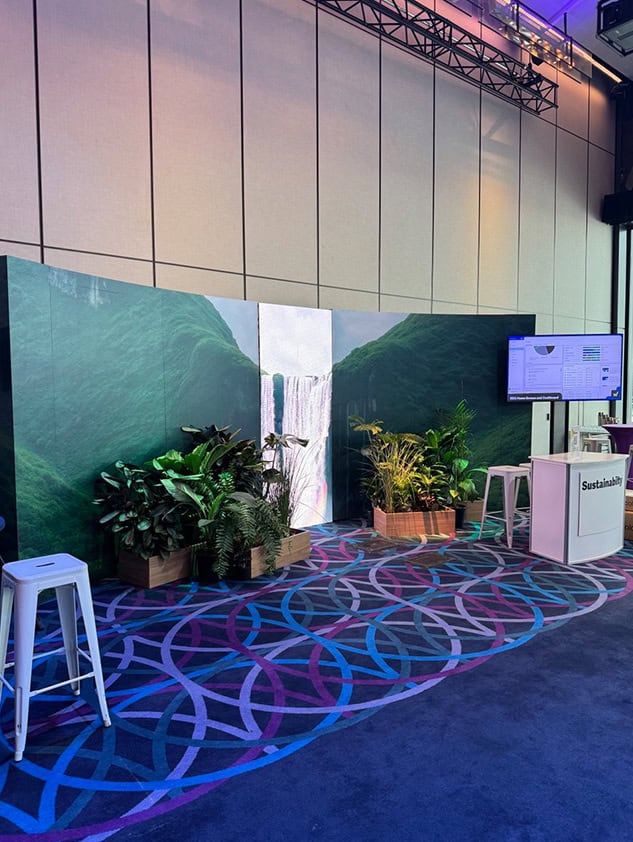 Networking event lounge with a green backdrop, plants and a patterned floor