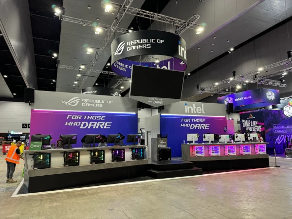 ASUS Republic of Gamers stand with gaming PCs and purple-lit counters under a hanging banner