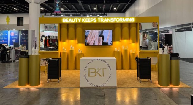 BKT Beauty Keeps Transforming exhibition stand with a lit yellow backwall