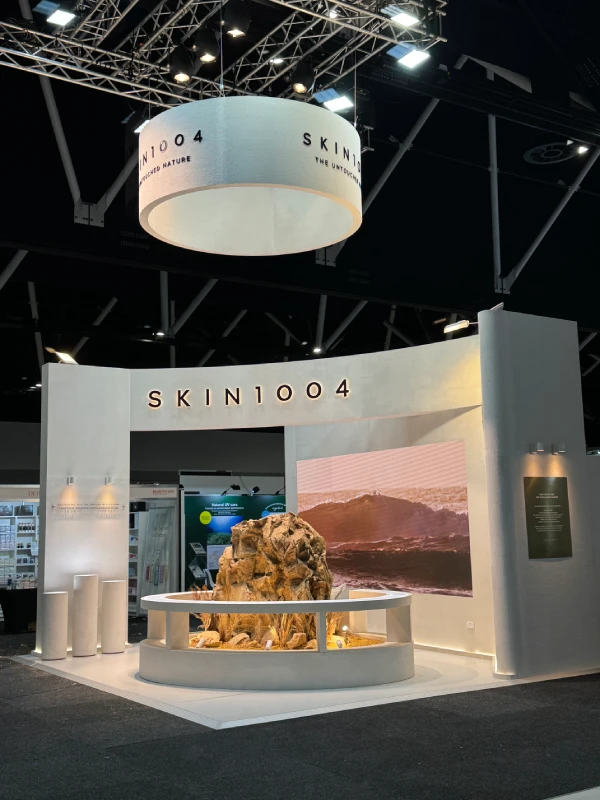 SKIN1004 exhibition stand with a curved white wall and a circular hanging sign