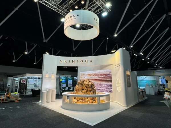 SKIN1004 exhibition stand with a curved white backwall, circular hanging sign and central display