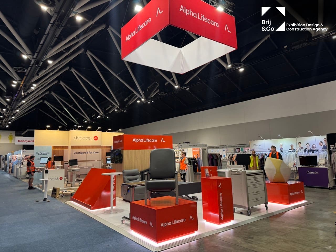 Alpha LifeCare exhibition stand with red display plinths and a hanging branded banner
