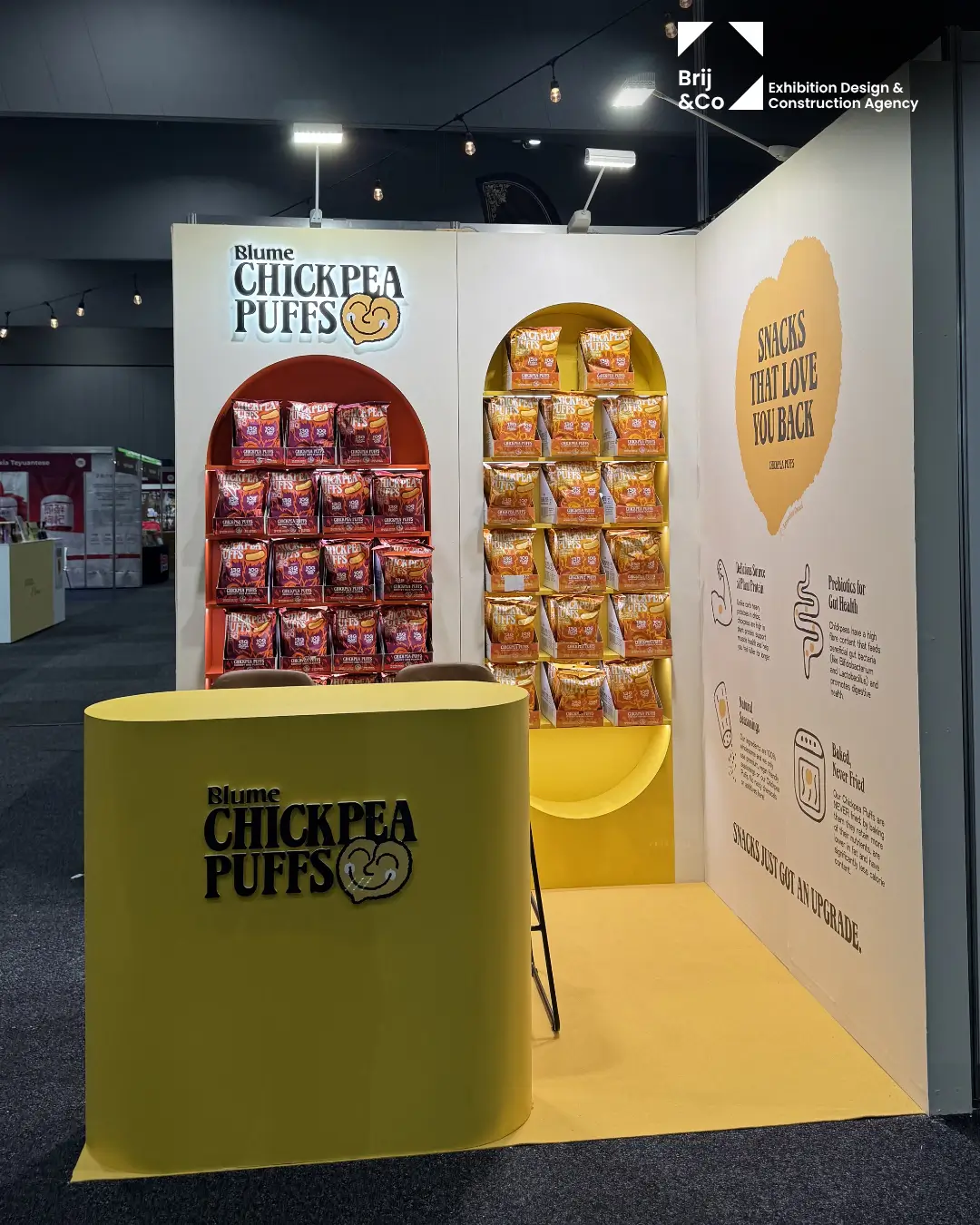 Blume Chickpea Puffs exhibition stand with product display wall and yellow counter