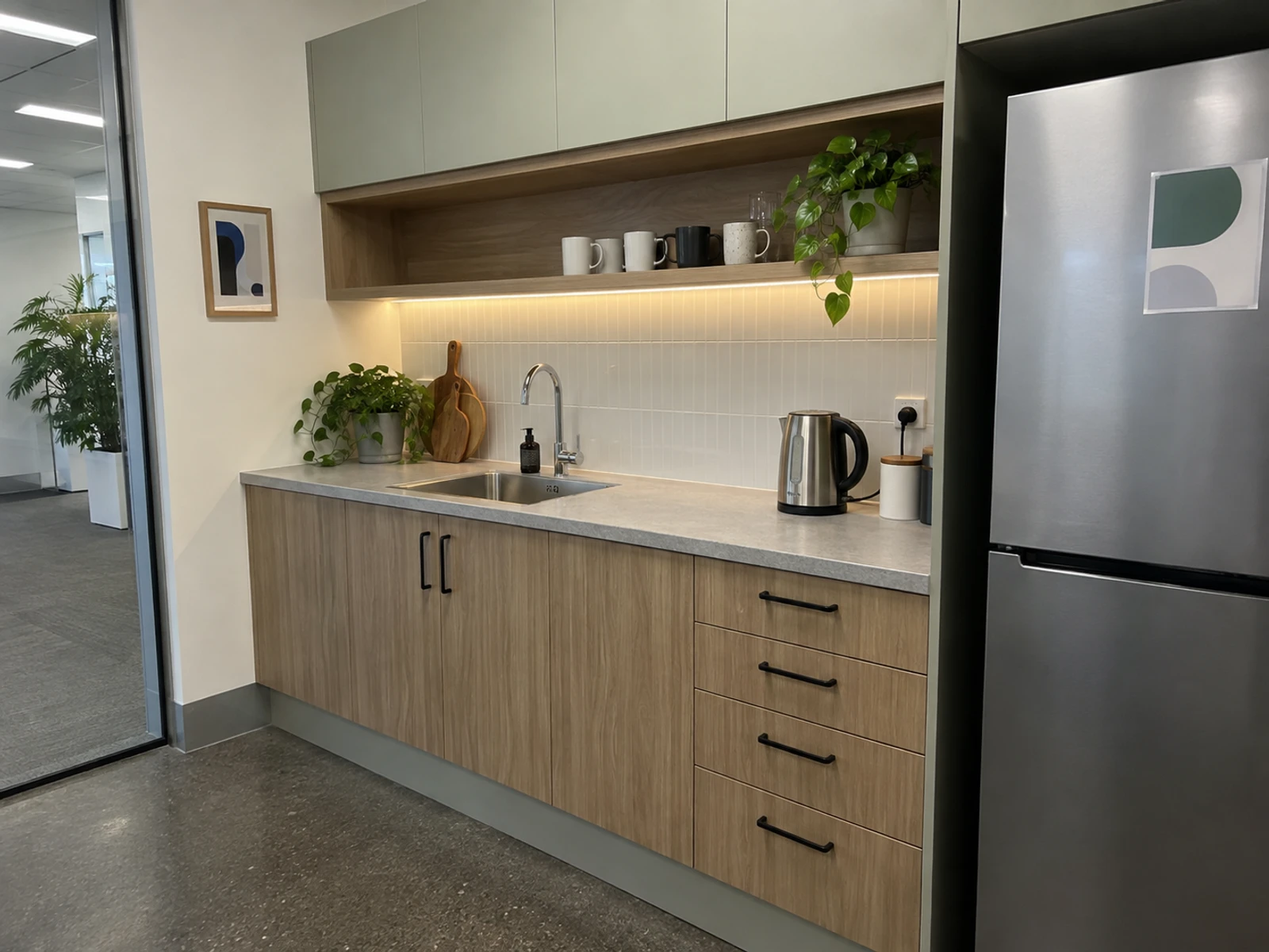 Office kitchenette with laminate cupboards, open shelves and a stone-look benchtop