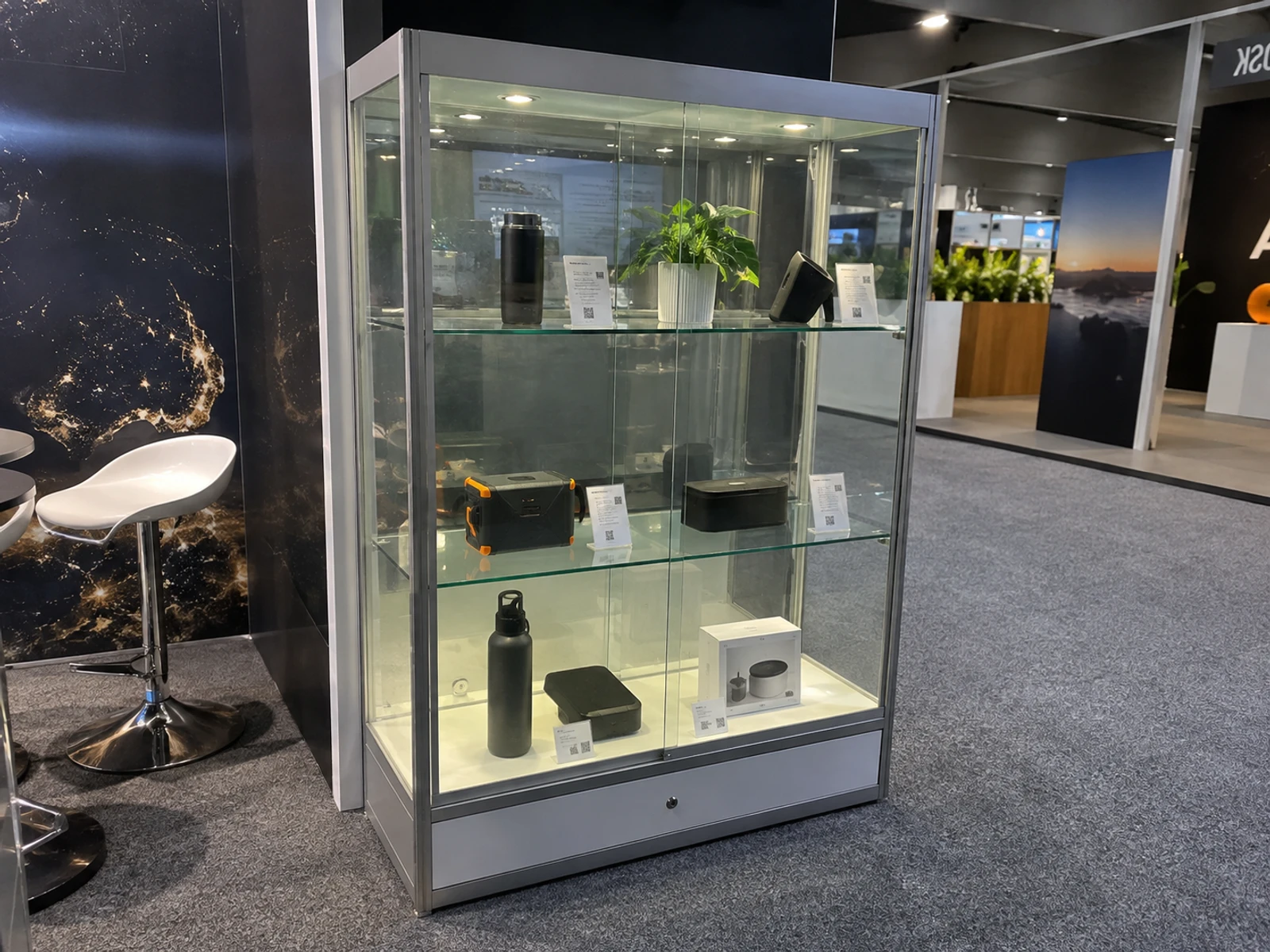 Lockable glass display cabinet on carpeted exhibition flooring with products inside