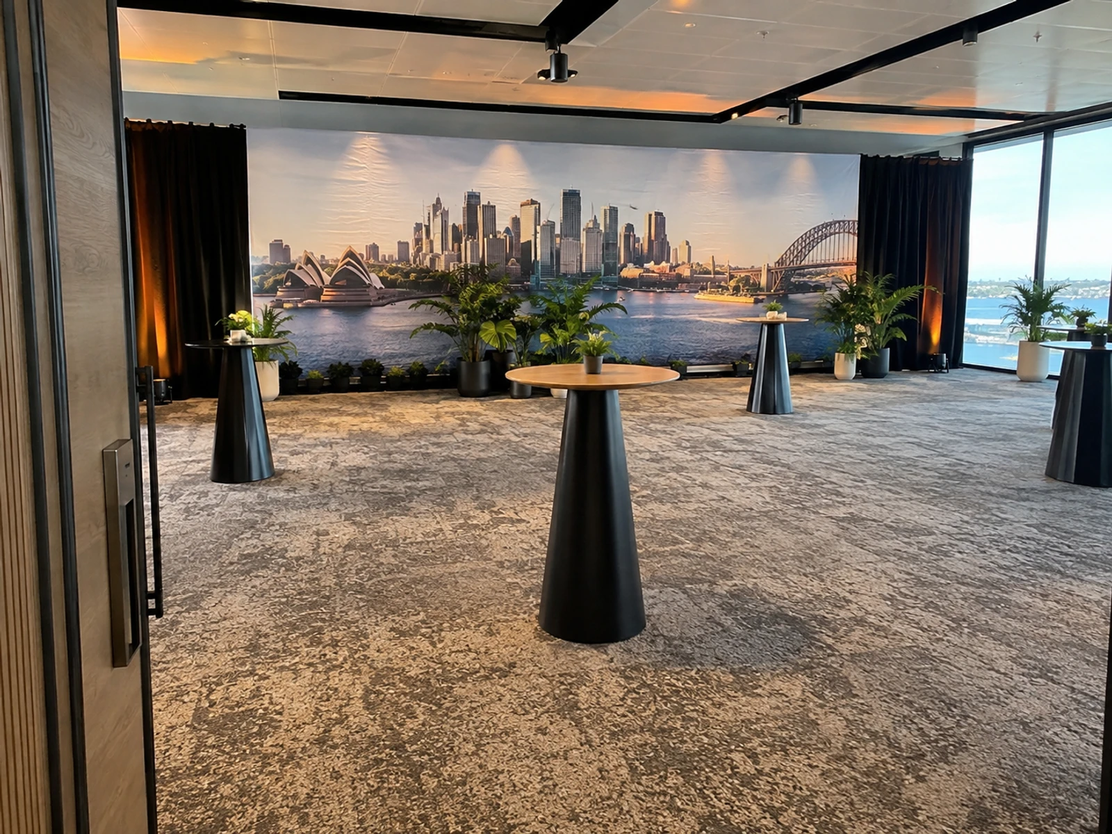 Printed backdrop set with planting and high tables ready for a networking event