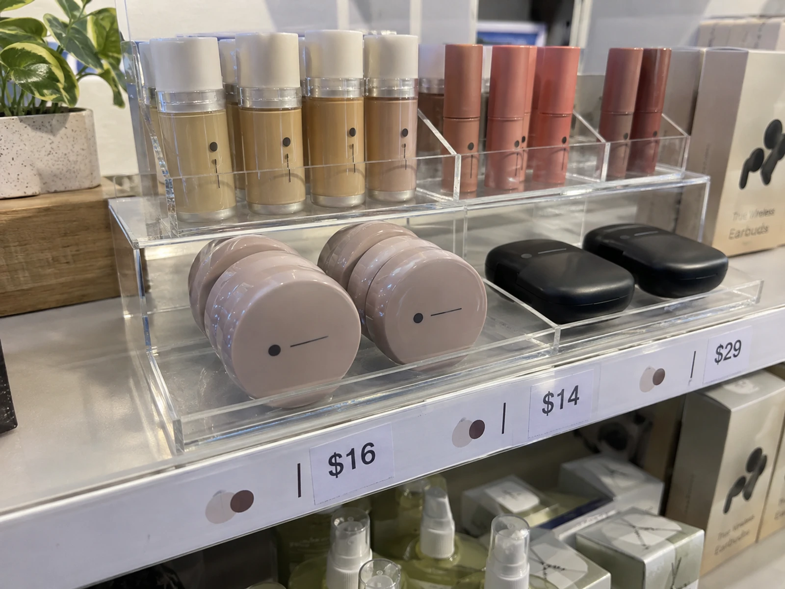 Clear acrylic tiered riser displaying cosmetic testers on a store shelf