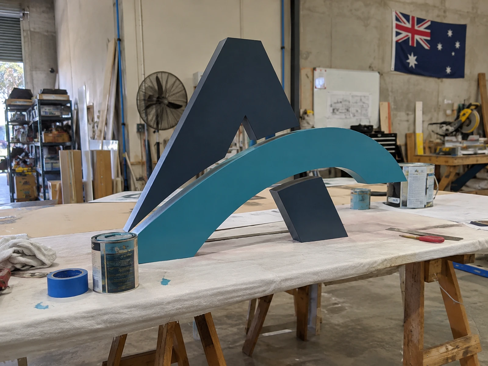 CNC-cut sculptural logo letters being painted in the workshop